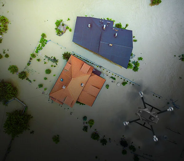 View of the disaster area from top, orange and blue roof of houses trees around there, cyberone Lite drone in grey and black colour is flying.