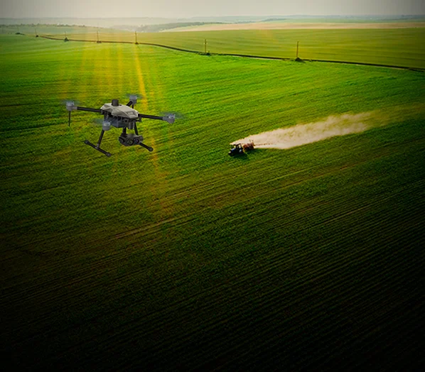 Vast green field, tractor is ploughing, and a cyberone drone is flying