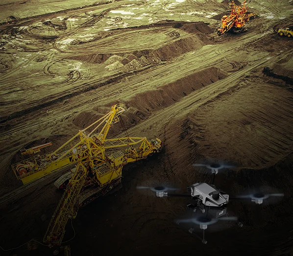 Yellow coloured crane with black cyberone drone on the sand and there is lining on the sand.